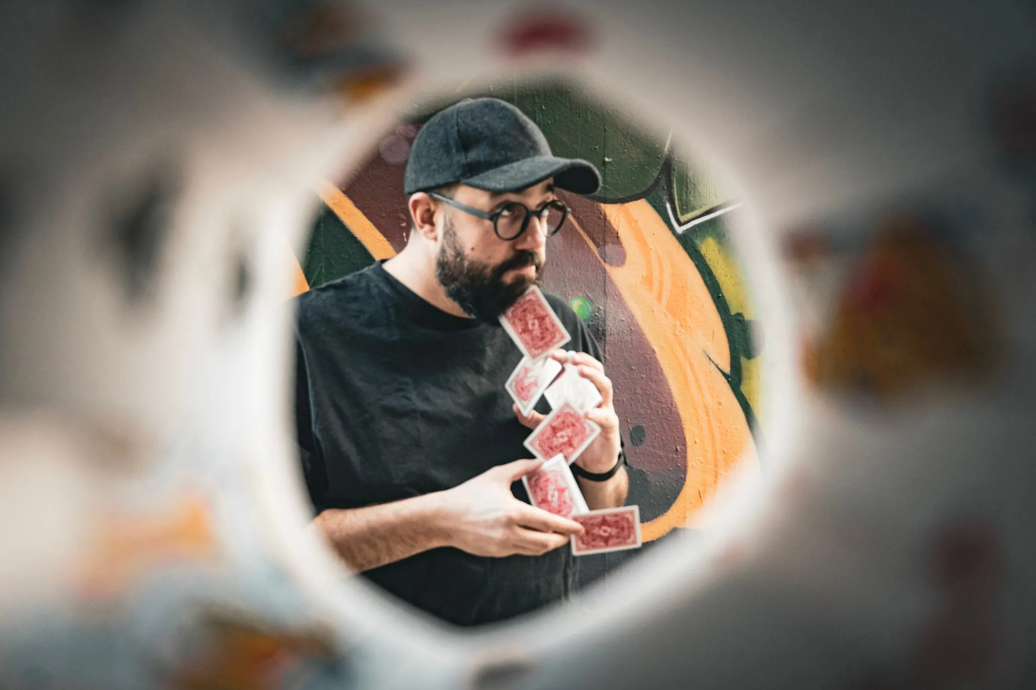 Manuel Kirsch mit Spielkarten, fotografiert durch einen Glasring.
