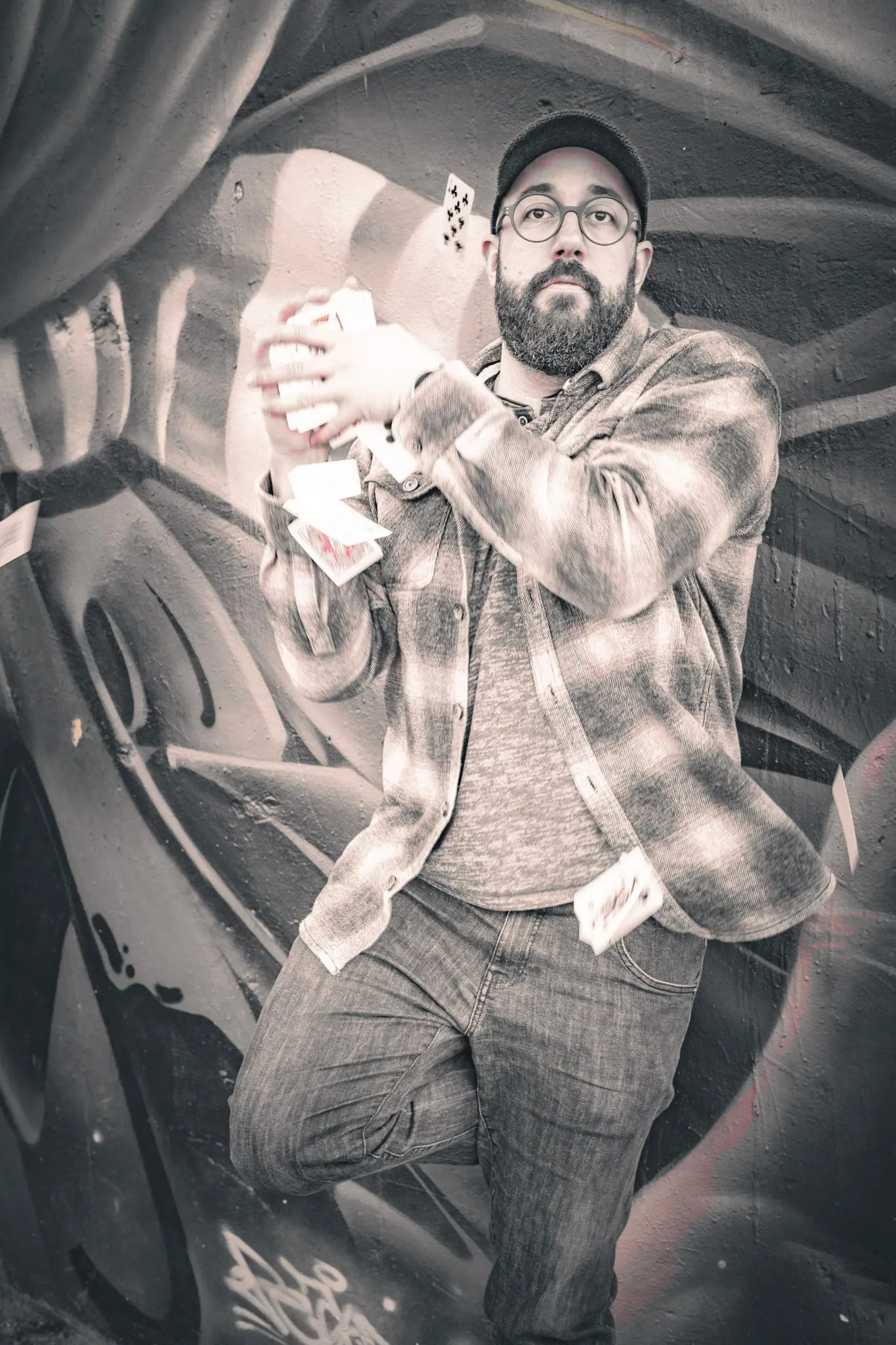 Schwarzweissfoto: Manuel Kirsch mit Karten vor einer Graffitiwand.