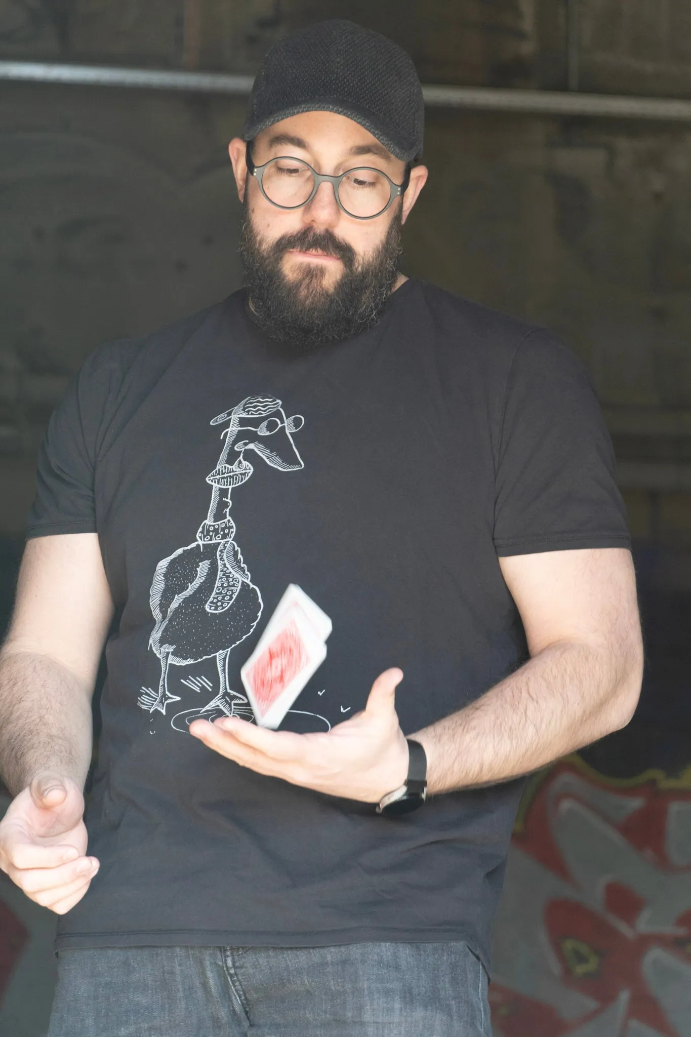 Manuel Kirsch im schwarzen T-Shirt schaut konzentriert auf ein Kartendeck, das zwischen seinen Händen durch die Luft fliegt.