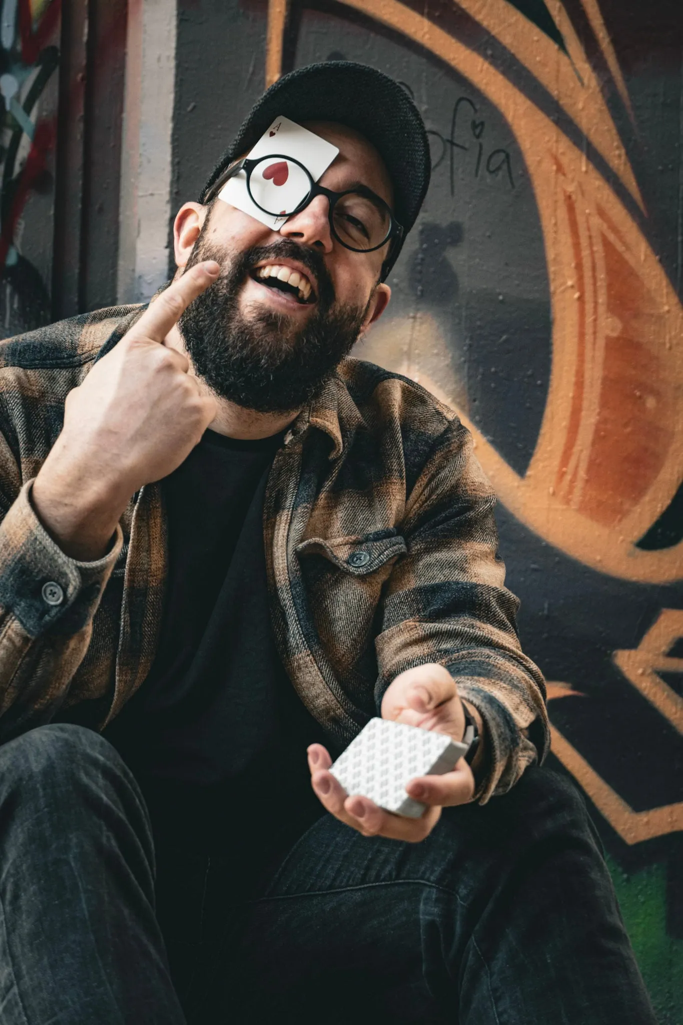 Manuel Kirsch lacht in die Kamera. Ein Herz-Ass klemmt hinter seiner Brille, in der Hand hält er ein Kartendeck.